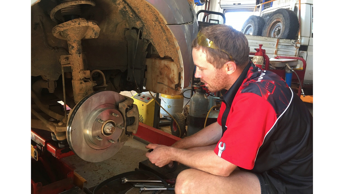 Mechanic checking disc rotors on car